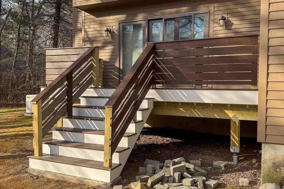 Angled view of the deck landing, grey stair treads and dark horizontal railings