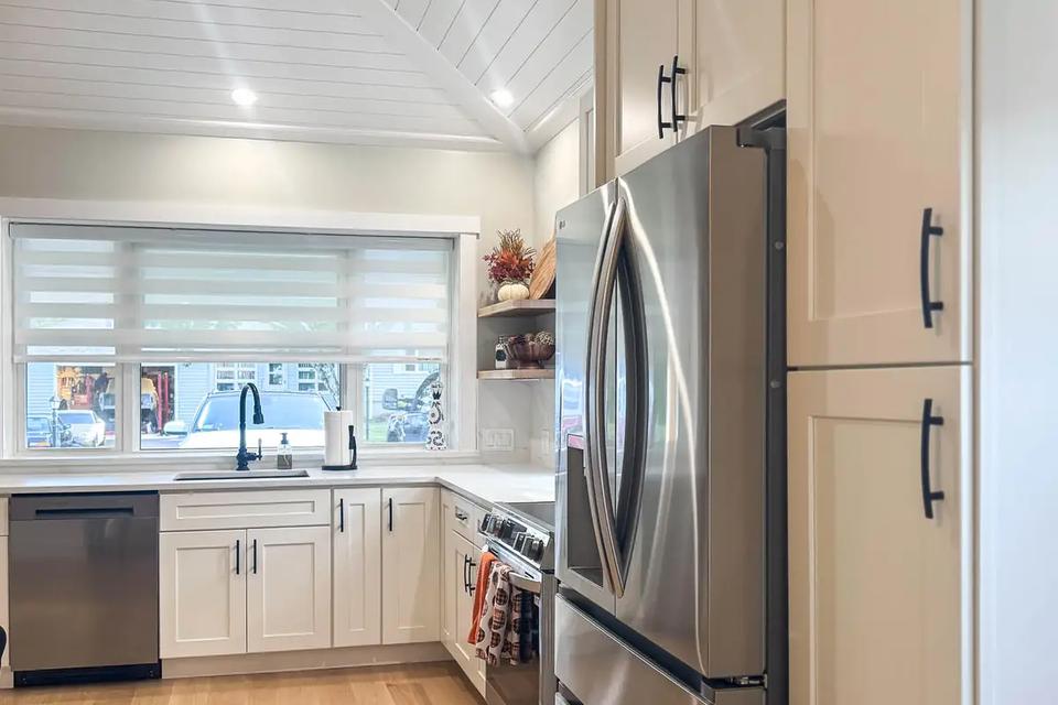 Stainless steel refrigerator and tall white cabinets beside the kitchen walkway