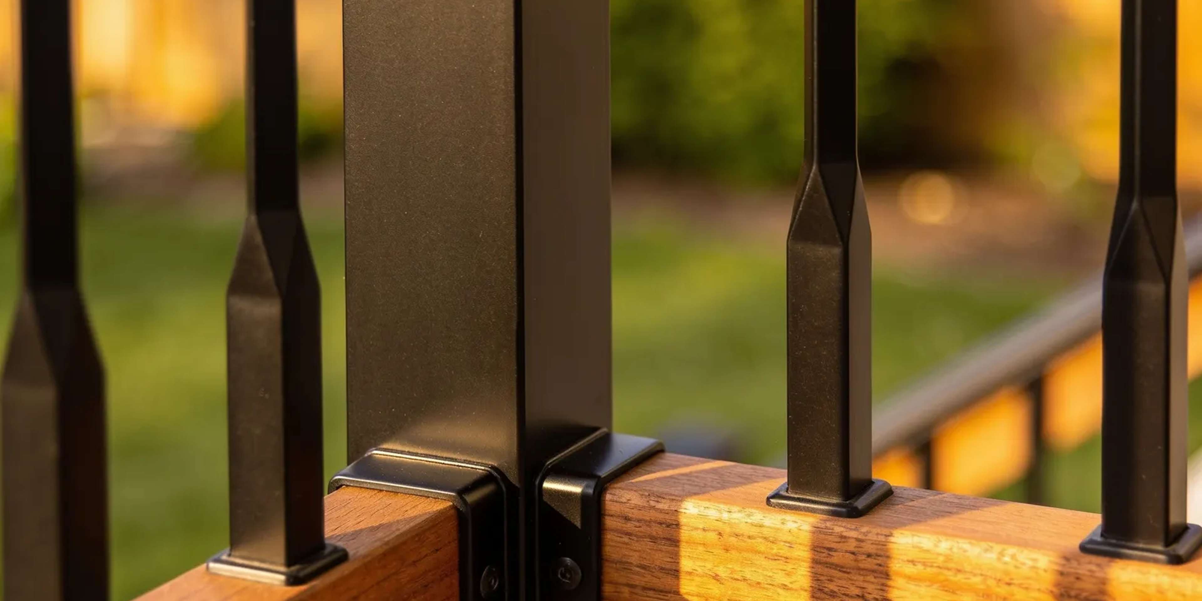 Modern deck railing with black aluminum balusters and a wood drink cap rail