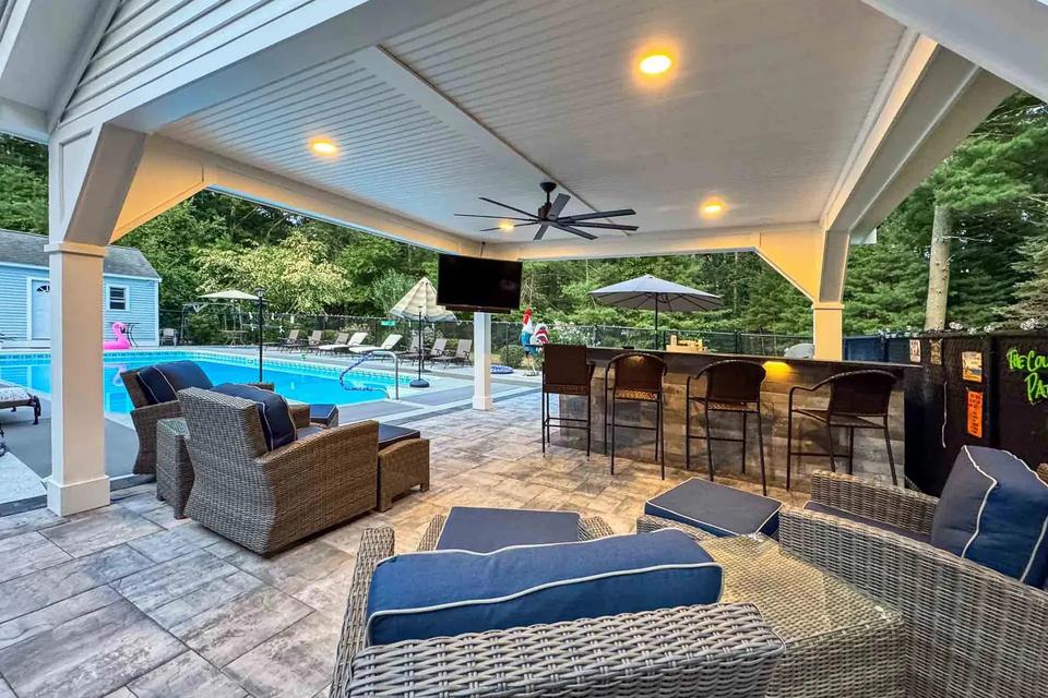 Wicker seating and a bar beneath the pavilion ceiling with recessed lights and a ceiling fan