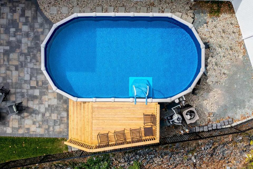 Top-down view of the above-ground pool and finished wood deck with railings