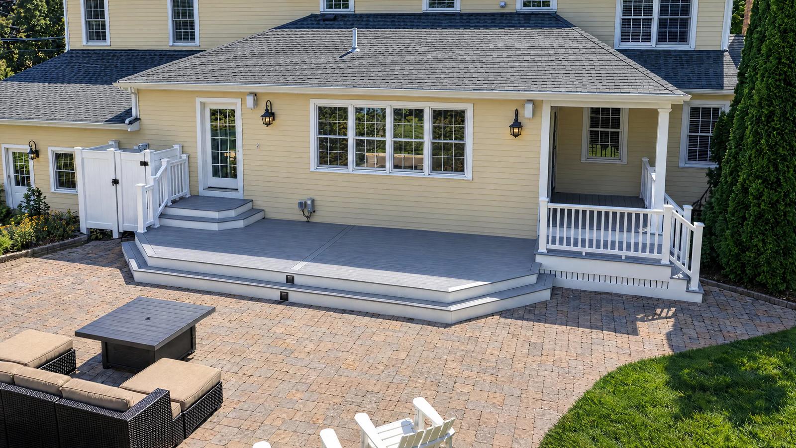 Angled daytime view of the grey backyard deck, wraparound steps and white porch railings in North Easton