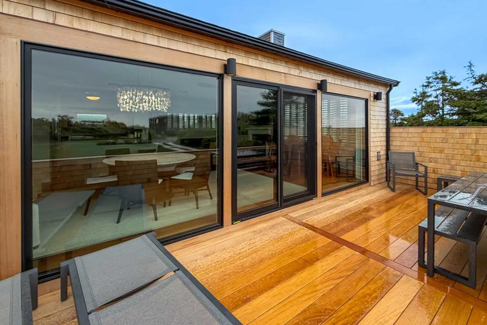 Garapa terrace with lounge chairs and a dining table outside black-framed glass doors
