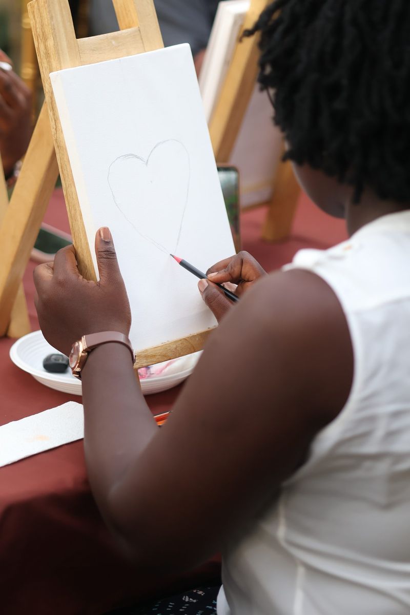A guest paints a heart on a canvas at an easel during the book club painting workshop