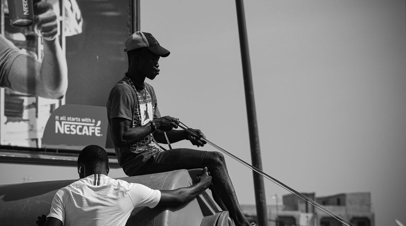 A young man holds the reins on a cart beside a large Nescafé billboard