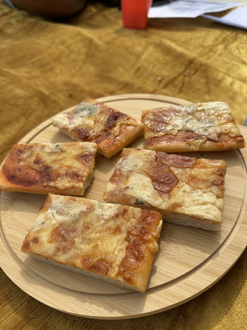 A plate of square-cut pizza slices on a wooden table at the beach picnic