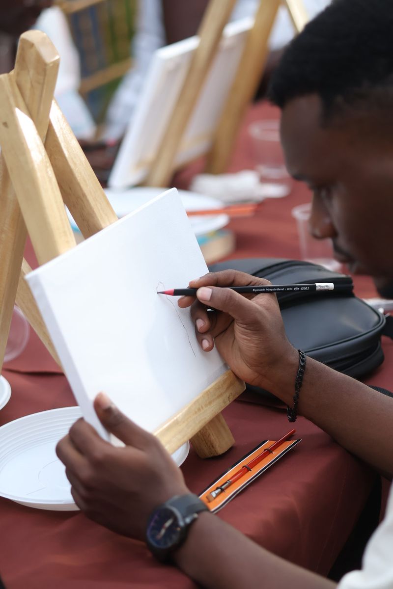 A guest sketches on a canvas at the painting workshop, a watch on the wrist