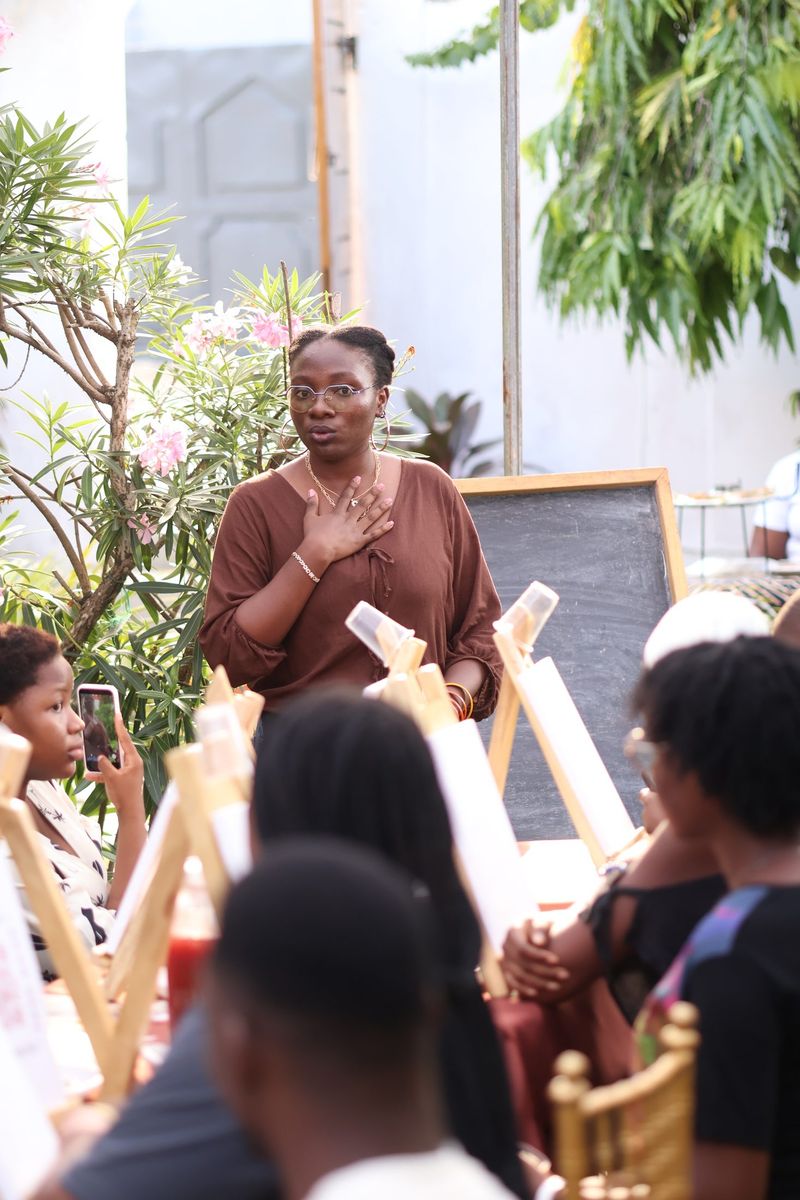 The host speaks to the book club audience among easels and greenery
