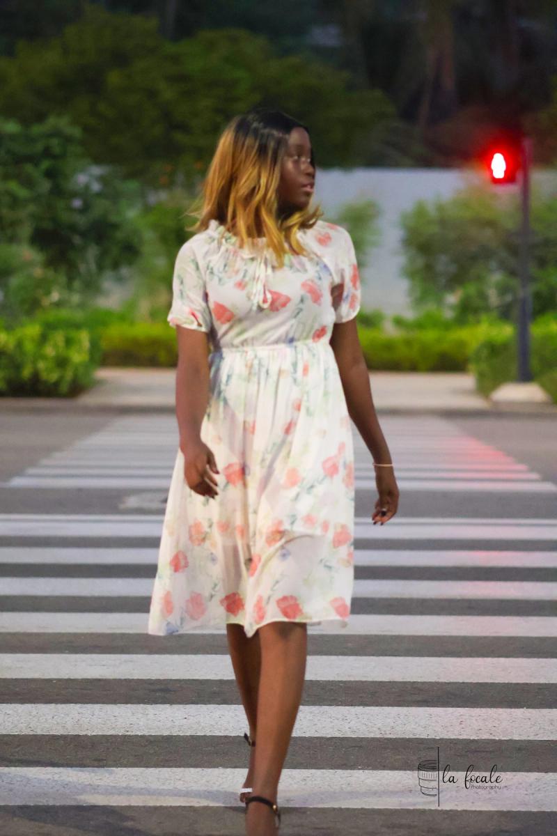Young woman in a floral dress crossing a pedestrian zebra crossing at dusk during a La Focale portrait shoot
