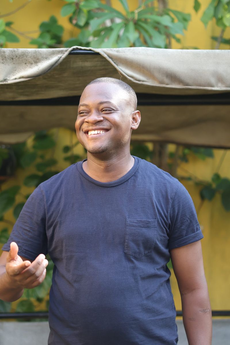 A man in a navy t-shirt laughs while speaking at the book club