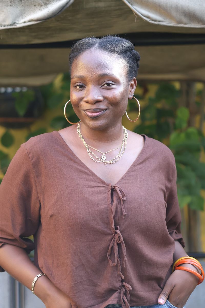 A smiling young woman in a brown top with hoop earrings poses at the gathering