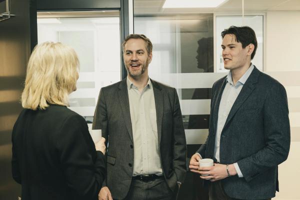 tre personer snakker på et kontor.