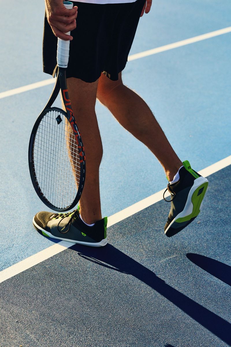 man walking on to tennis court wearing atomic court onyx ecto colorway