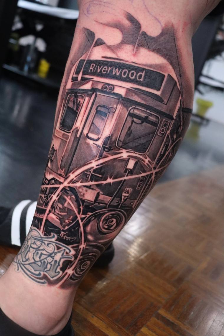 Freshly tattooed black and grey realism piece on a calf depicting a subway train with a Riverwood destination sign and graffi