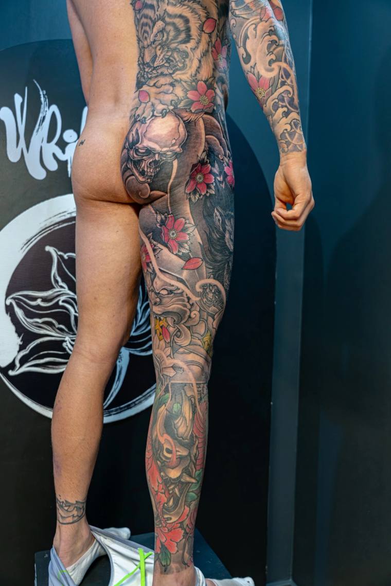 Finished full-leg irezumi sleeve featuring a hannya mask, dragon, cherry blossoms, and koi fish in color, photographed in a t