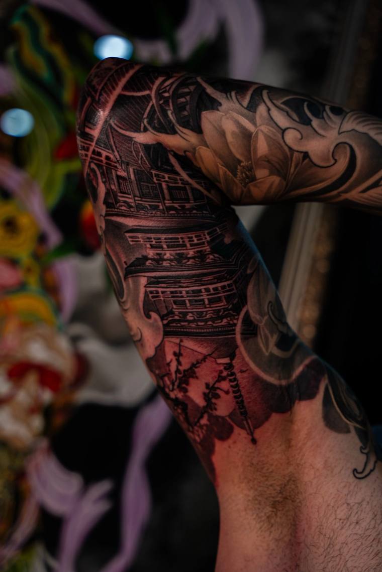 Finished black and grey irezumi tattoo on a shoulder and upper arm featuring a multi-tiered pagoda, cherry blossoms, wind bar