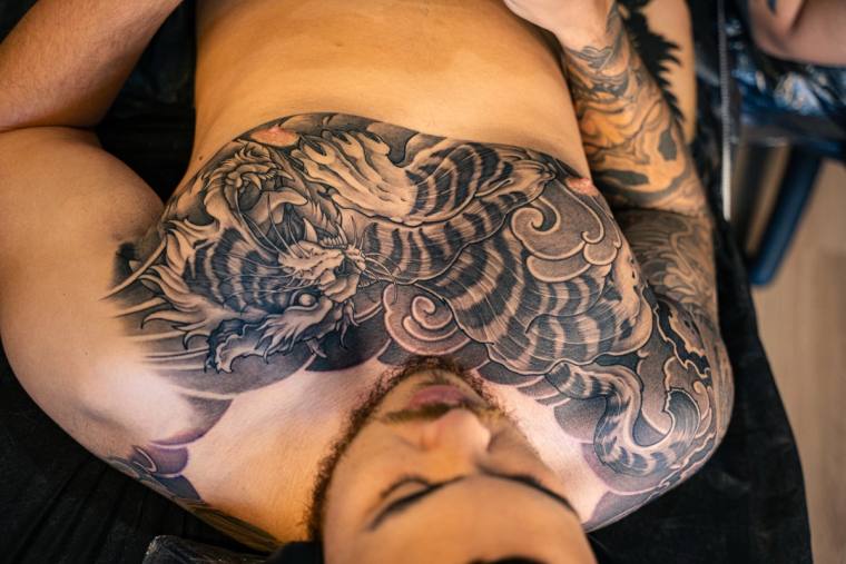 Finished Japanese irezumi chest piece featuring a snarling tiger and dragon in black and grey, photographed on the client.