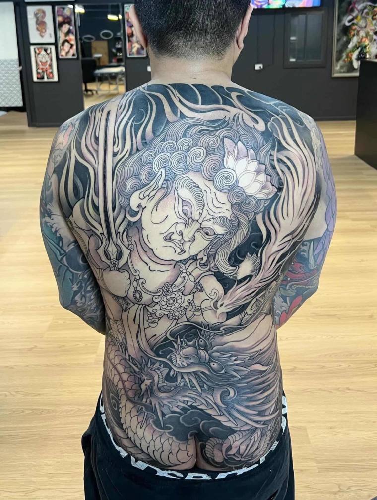 Finished irezumi full back tattoo featuring a hannya mask, soaring phoenix, dragon, lotus, and swirling clouds in black and g