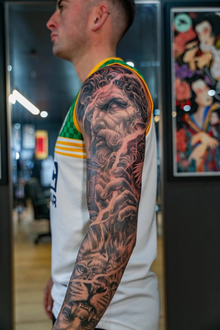 Detailed blackwork full sleeve tattoo featuring a bearded classical god with flowing hair, lightning bolt, and a tiger face n