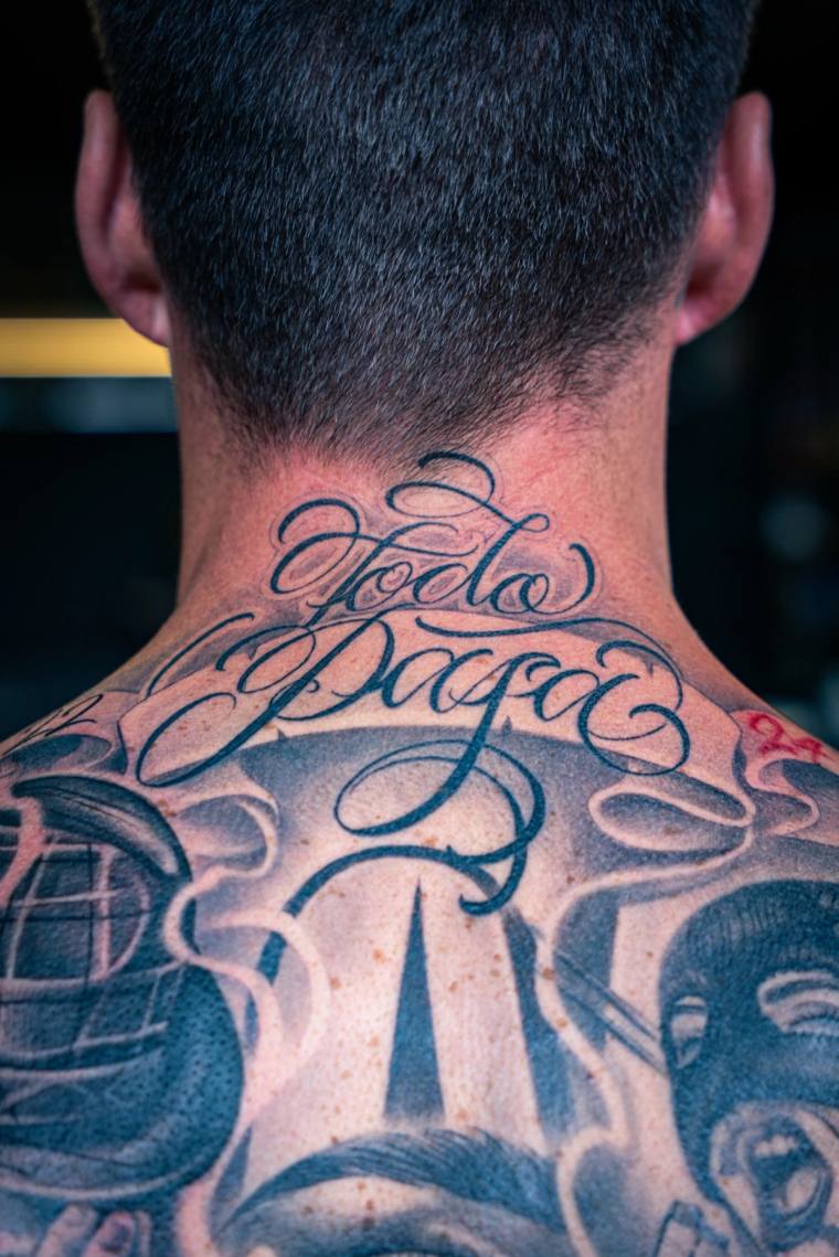 Close-up of a finished irezumi tattoo across the back of the neck and upper back, featuring elegant cursive script above shad