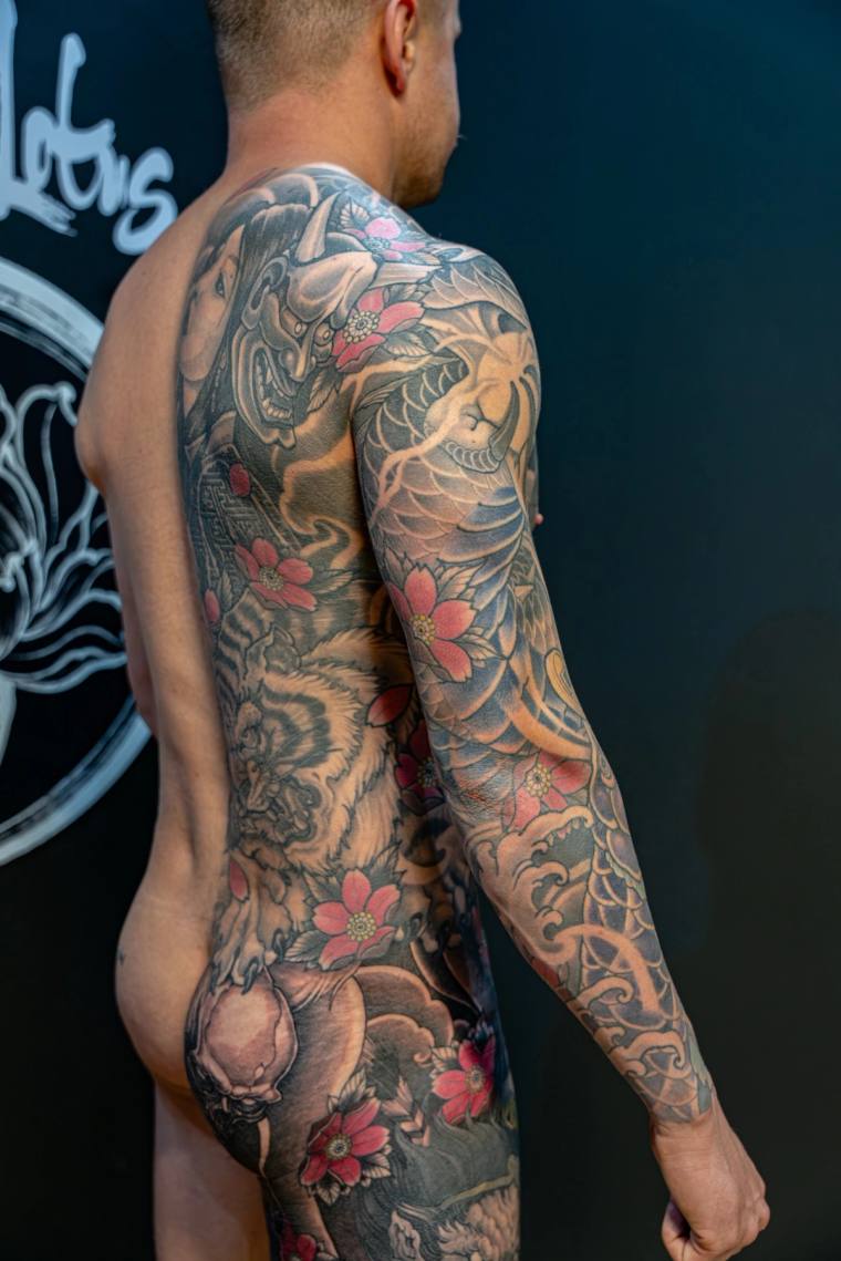 Japanese irezumi full sleeve and back tattoo featuring a hannya mask, dragon, koi, foo dog, lotus, and pink cherry blossoms i