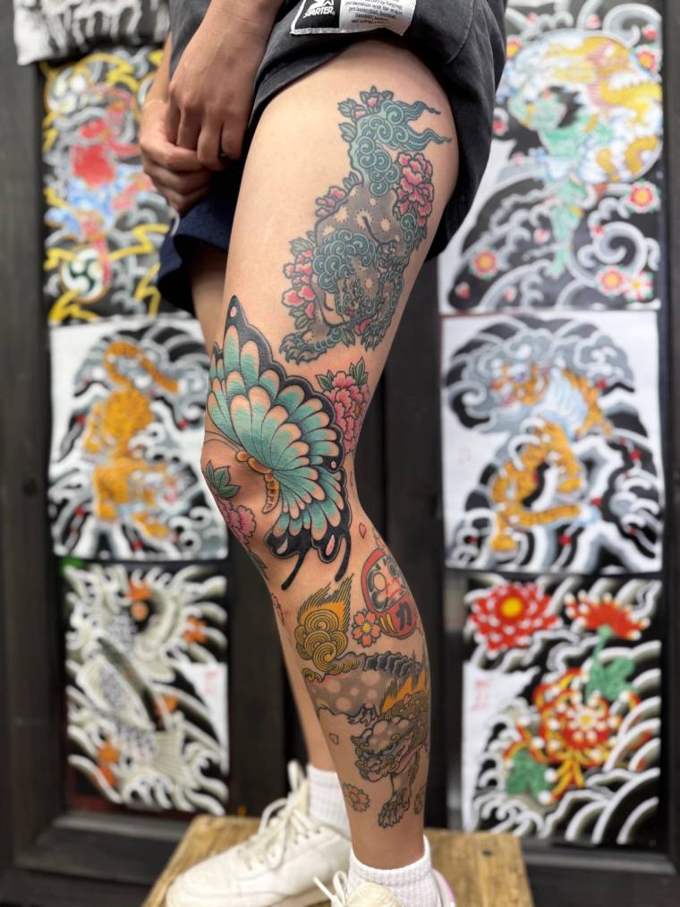 Finished irezumi leg sleeve featuring a turquoise butterfly, foo dog, cherry blossoms, daruma doll, and mythical lion-dog on 