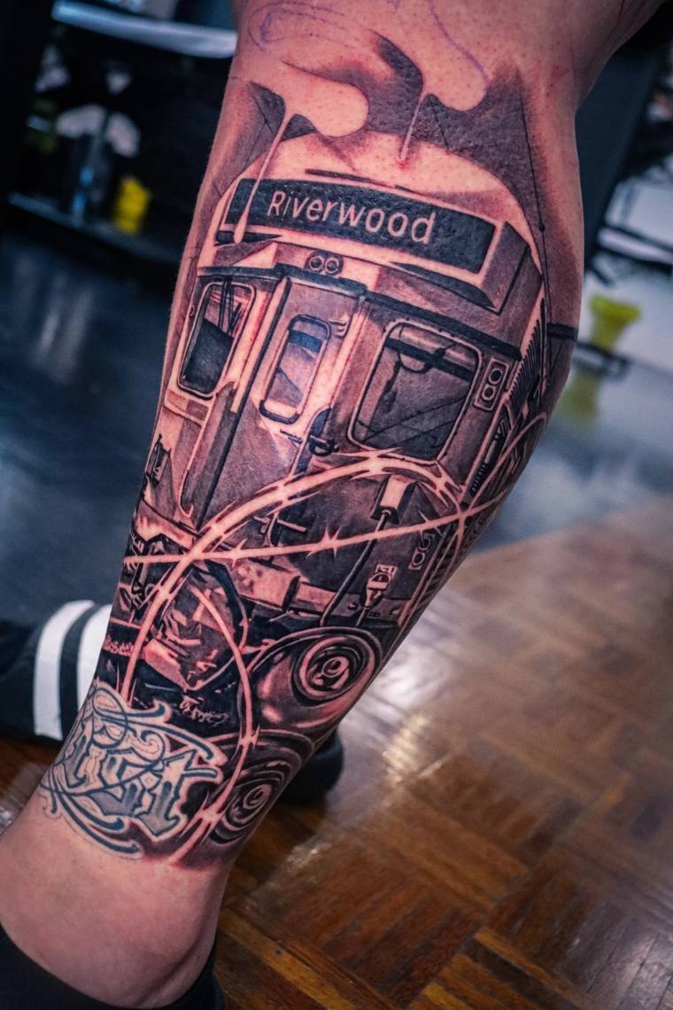 Blackwork tattoo on a calf depicting a detailed subway train car with a 'Riverwood' destination sign and graffiti-style lette