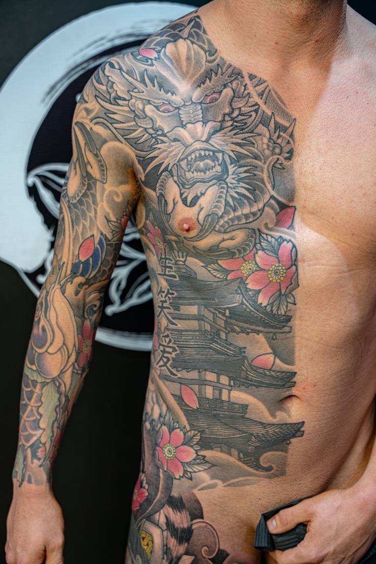 Finished irezumi half-sleeve and side panel featuring a snarling Hannya mask, pink cherry blossoms, a pagoda, kanji, and koi 