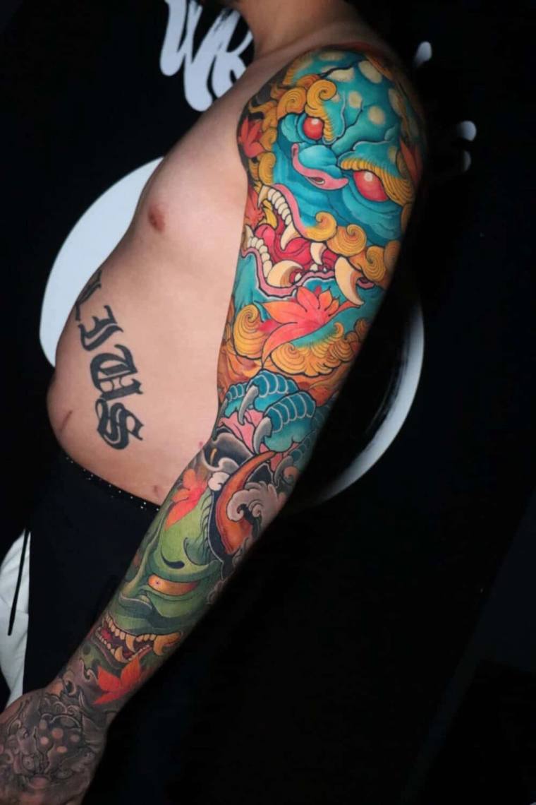 Finished colour irezumi full sleeve featuring a teal fudo demon mask with bared fangs, golden mane, a green oni face near the