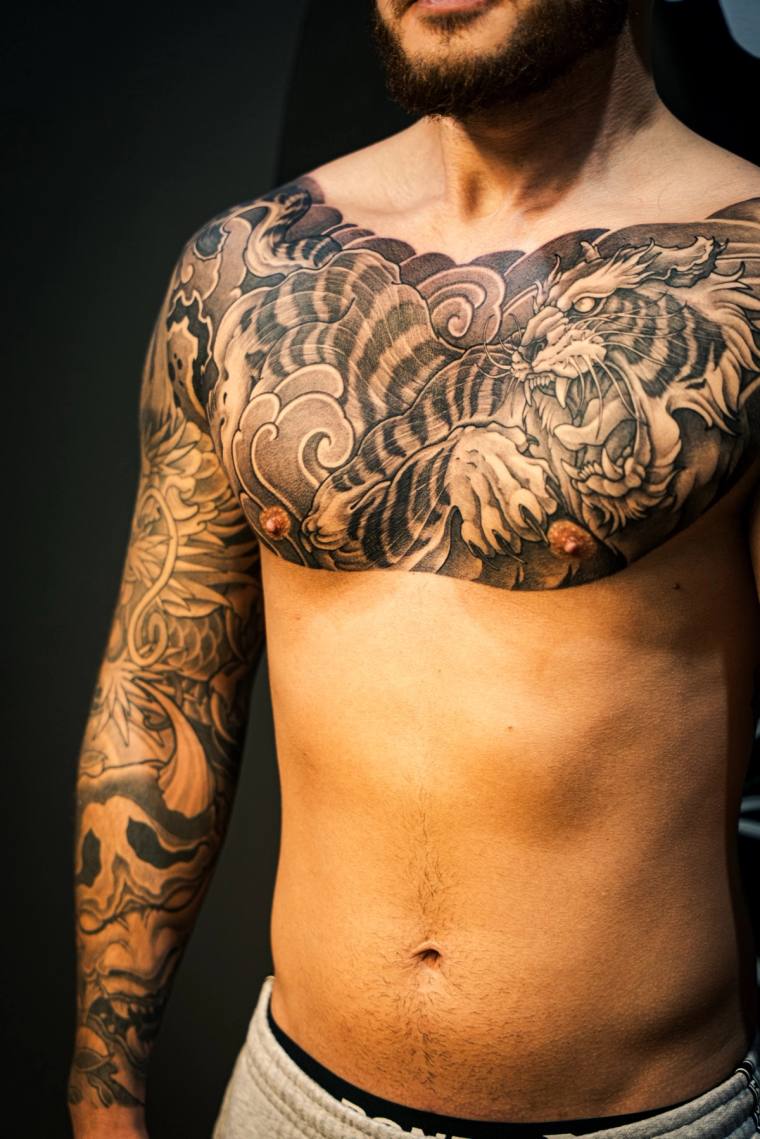 Finished irezumi chest and right arm tattoo featuring a snarling tiger and crashing waves in black and grey.