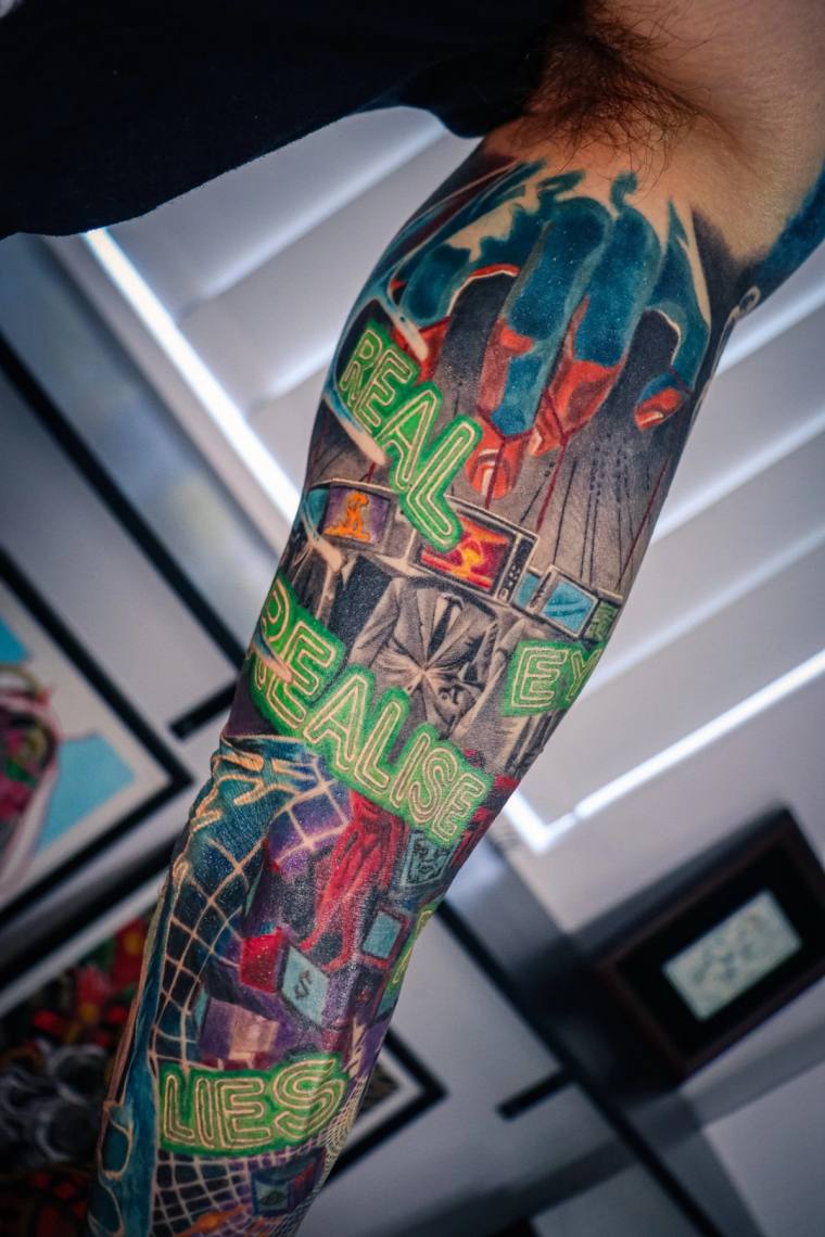 Vibrant full forearm sleeve featuring neon-green 'REAL' and 'REALISE LIES' text layered over a colorful urban cityscape with 