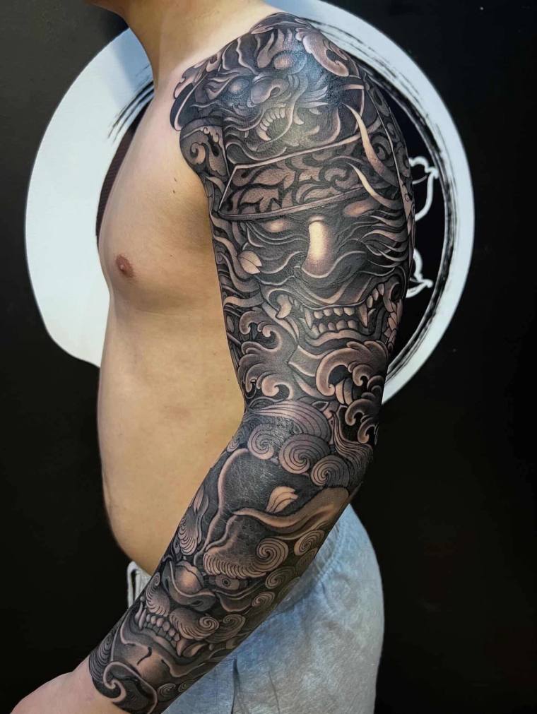 Finished greywash Japanese-style full sleeve tattoo featuring a hannya mask, oni demon face, and traditional swirling clouds 