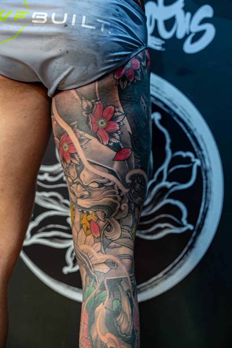 Full colour irezumi leg sleeve featuring a hannya mask, red peonies, cherry blossoms, and a traditional Japanese figure on th
