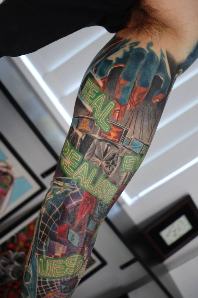Finished forearm sleeve tattoo featuring neon-style lettering reading 'REAL', 'REALISE', and 'LIES' in green, red, and black 