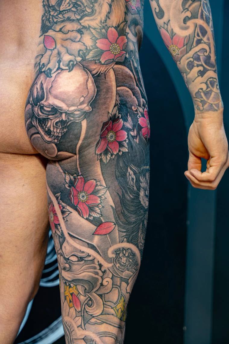 Finished irezumi leg sleeve featuring an oni skull, red cherry blossoms, peonies, a tiger, snake, and swirling clouds in blac