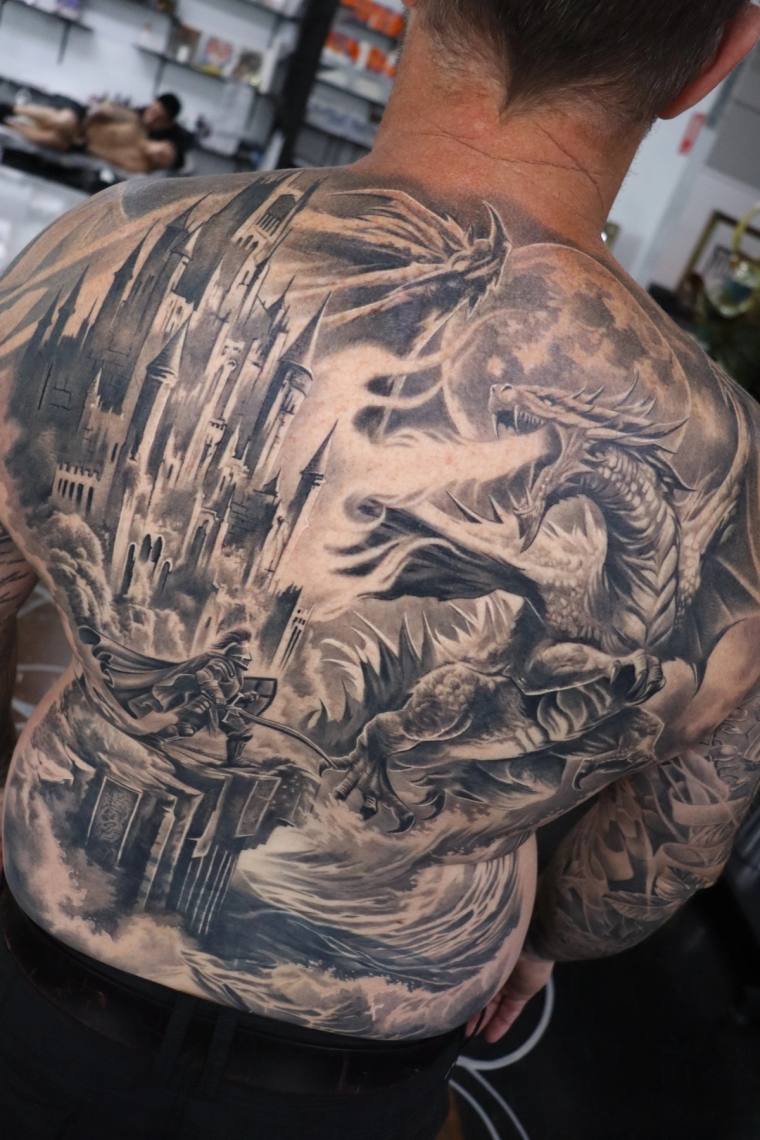 Large black and grey irezumi back piece featuring a dragon, traditional Japanese temple, modern cityscape, and full moon.