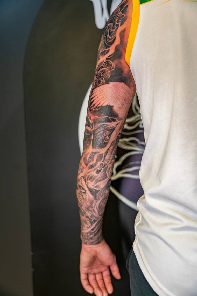 Finished blackwork irezumi full sleeve featuring a snarling tiger among crashing waves and traditional Japanese clouds on a m