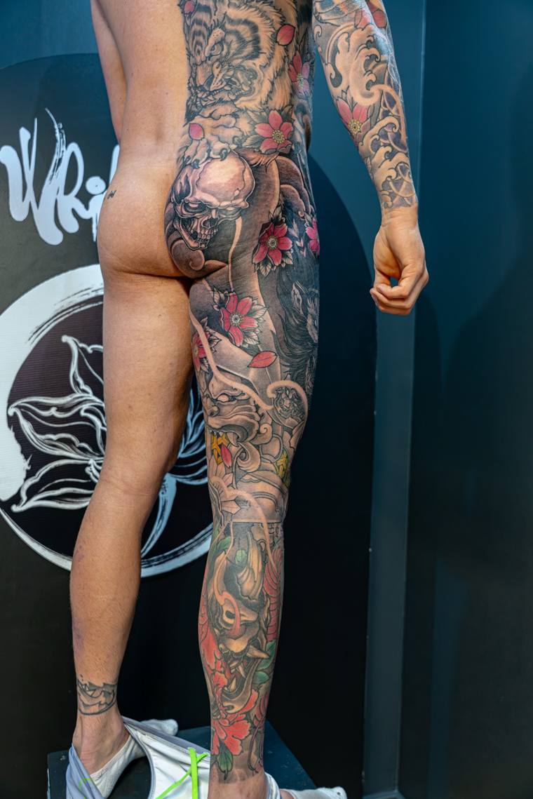Finished full-leg irezumi sleeve featuring a hannya mask, dragon, cherry blossoms, and koi fish in color, photographed in a t
