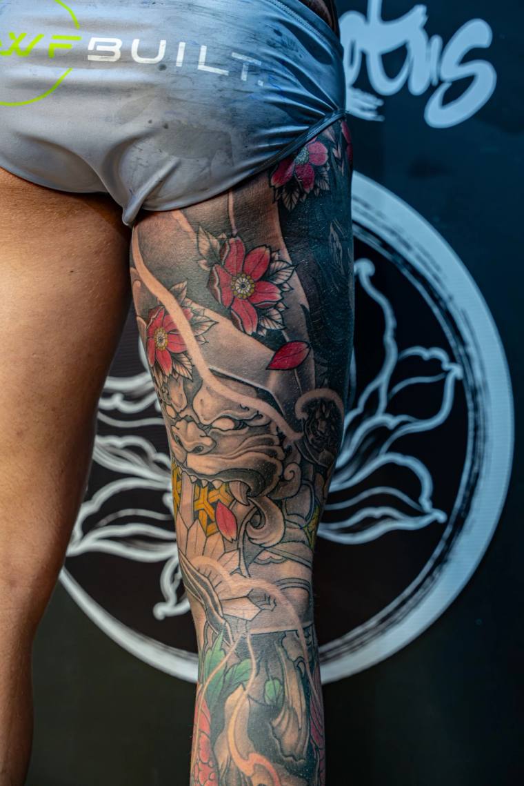 Finished irezumi leg sleeve featuring a shishi (foo dog) face, red cherry blossoms, clouds, and green foliage on a client's t