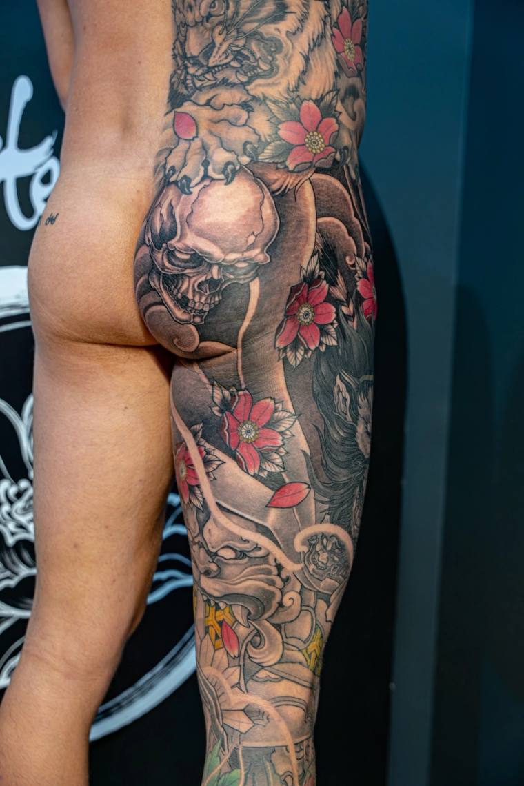 Finished irezumi full sleeve featuring a smoking skull, red cherry blossoms, koi fish, and traditional Japanese mask on the u