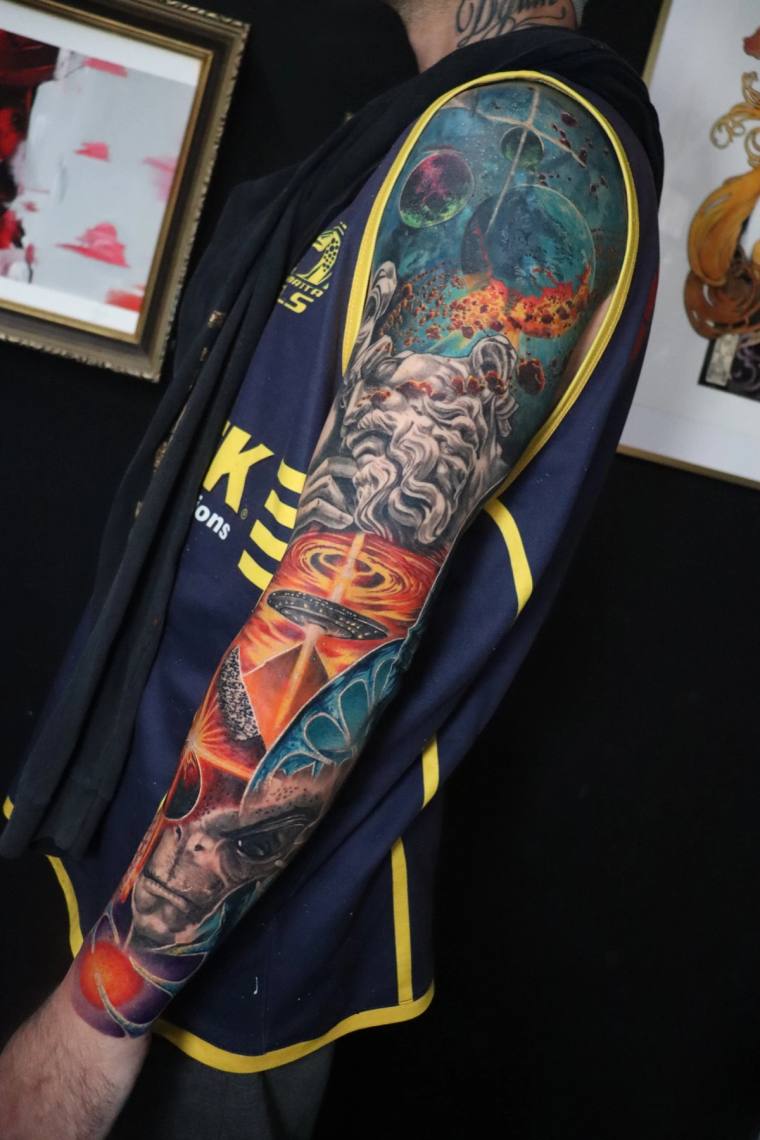 Finished full-sleeve tattoo featuring a realistic bearded god, planets, cosmic nebula, black hole and alien head rendered in 