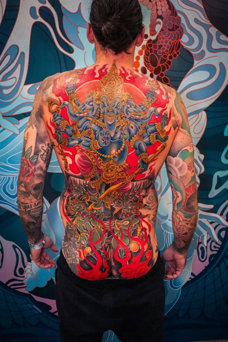 Healed full-back irezumi piece featuring a multi-armed elephant-headed deity with crown above a writhing dragon surrounded by