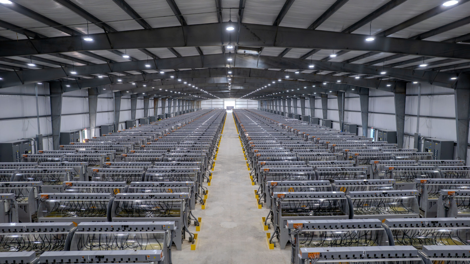 Picture of Riot Platforms Corsican Facility, depicting an industrial size Bitcoin mining operations with thousands of Liquid cooled Bitcoin miners in a large warehouse
