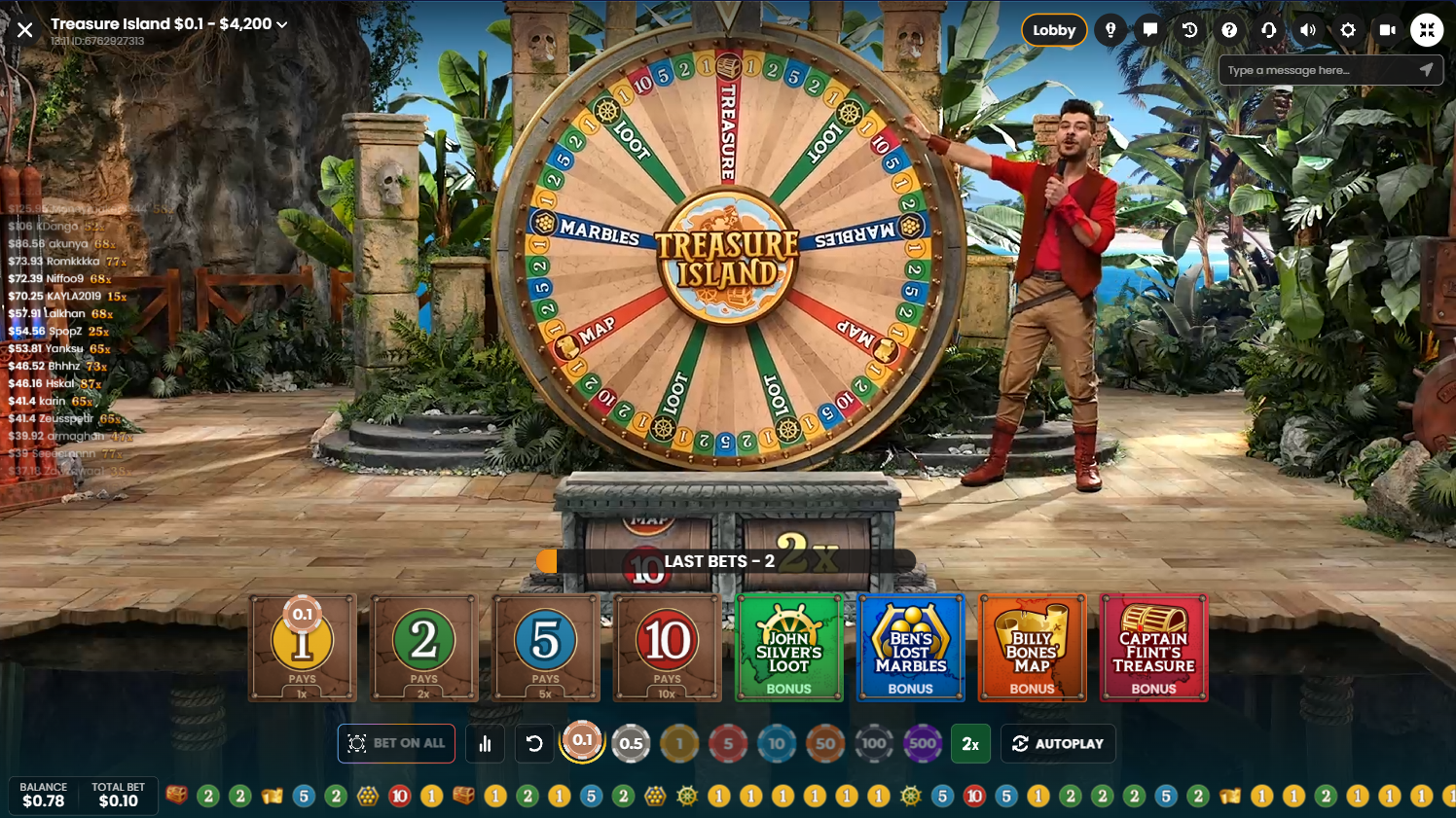 Pragmatic PlayのTreasure Island Live Casinoのマネーホイールを回す男性ホストと、その下のベット画面 - Flush