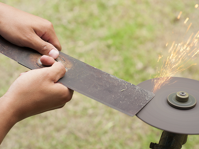 Person sharpening mower blade