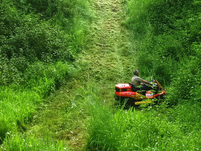 man going up slope in ride on mower