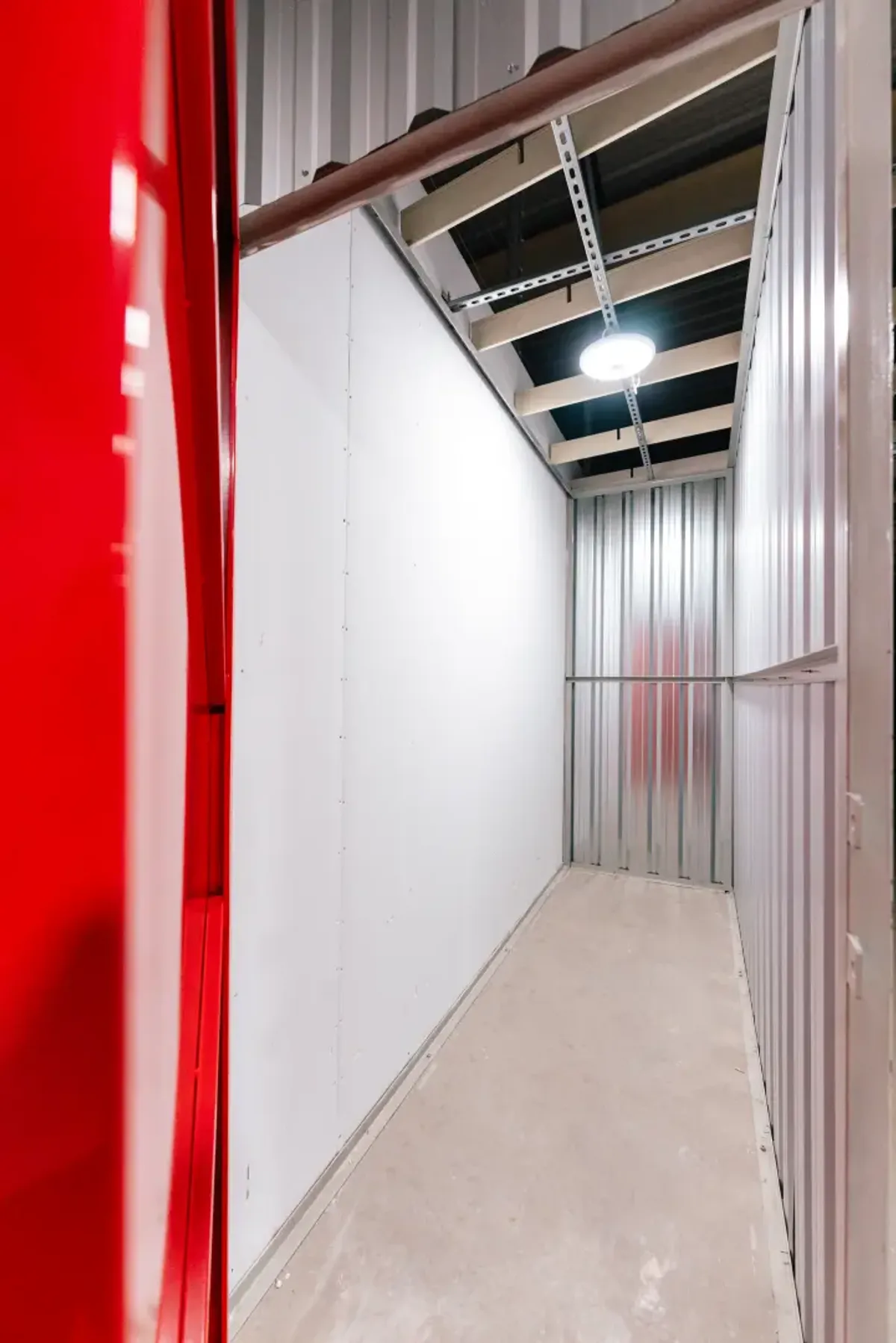 Wnętrze małego boksu magazynowego w Celtic Self Storage Łomianki — czerwone drzwi i oświetlenie