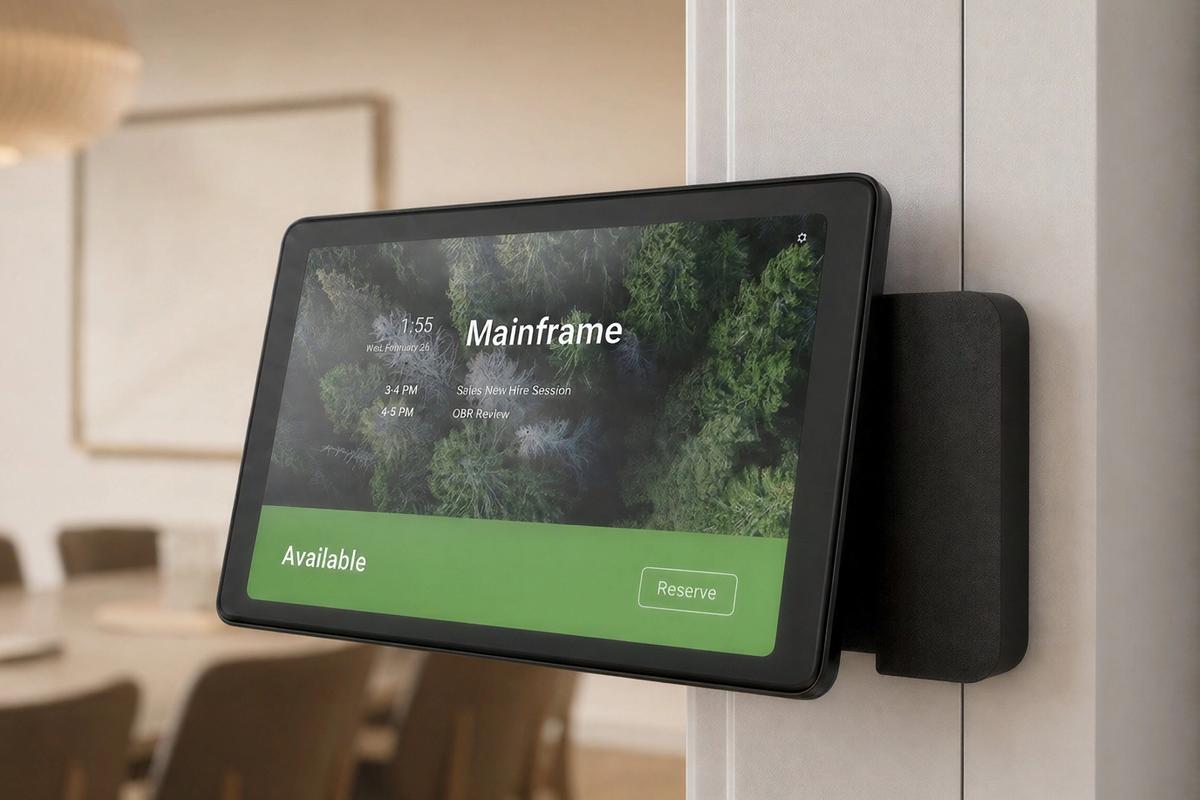 Wall-mounted tablet and meeting room technology in a modern workplace.