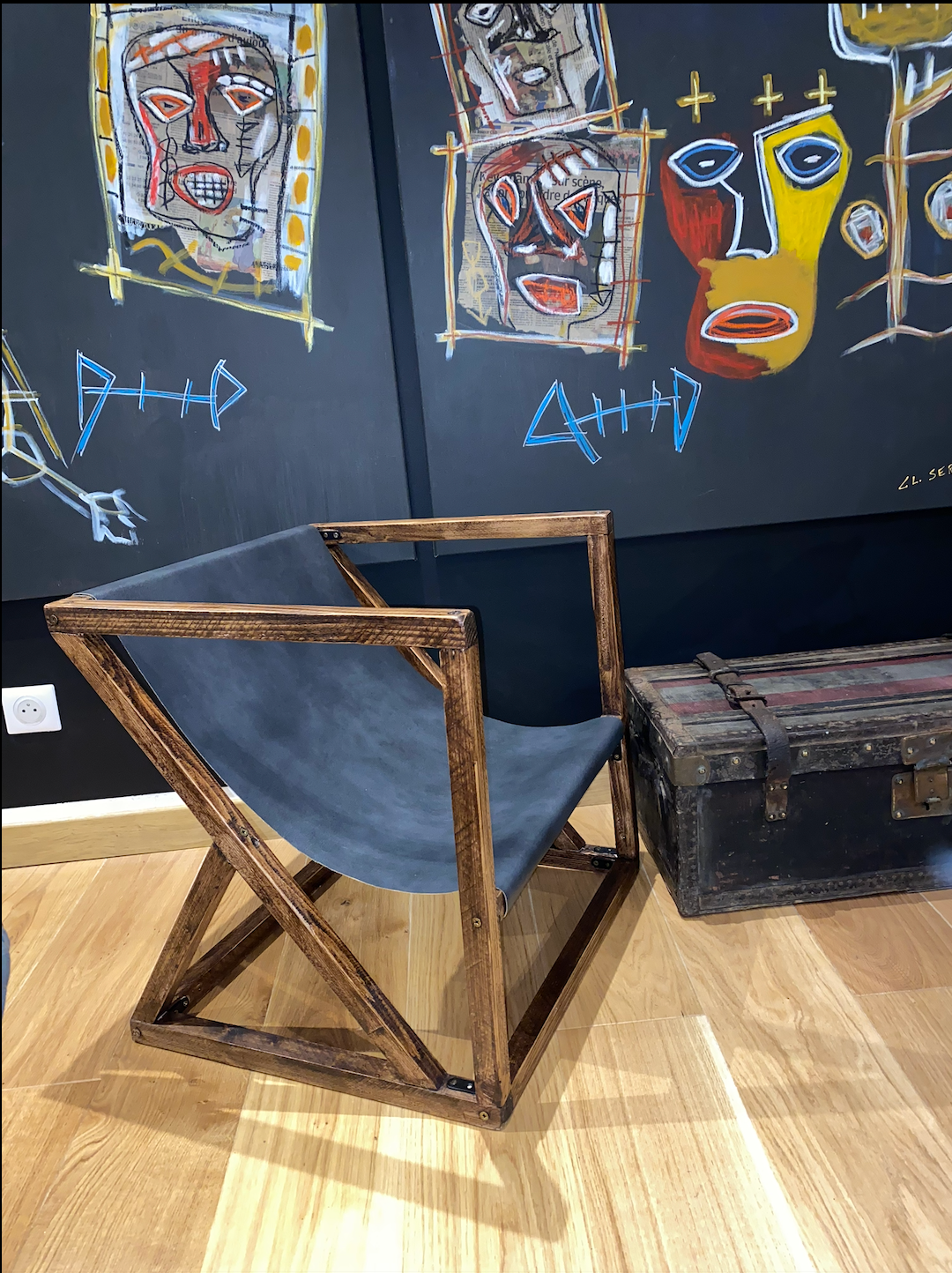 La chaise terminée : structure en bois teinté à lignes obliques et assise de cuir noir