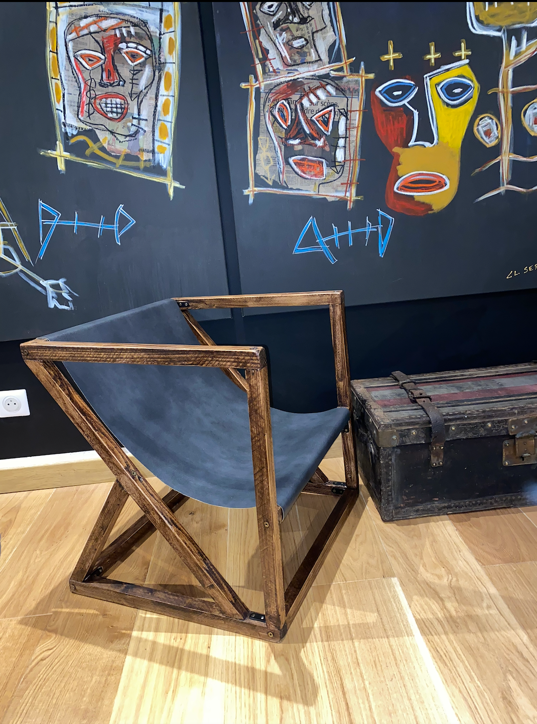 La chaise terminée : structure en bois teinté à lignes obliques et assise de cuir noir